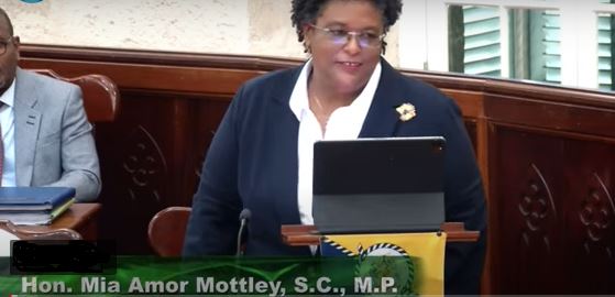 Image of Barbados Prime Minister, Hon. Mia Mottley, presenting the budget, with a Member of Parliament sitting on her right hand side.